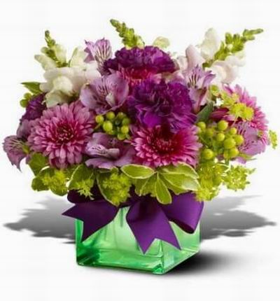 Lavender and green bouquet. A range of blossoms in gentle shades of purple and chartreuse in a green glass cube vase