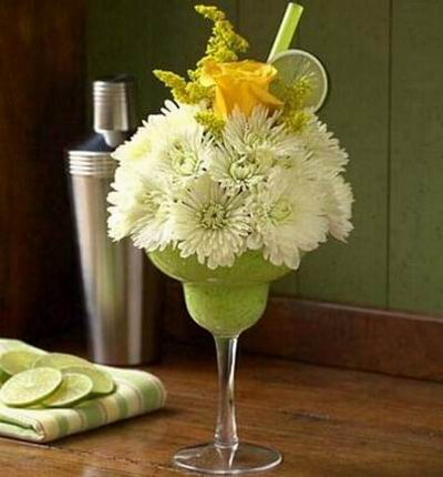 White cushion poms inside a reusable acrylic margarita glass is topped off with a yellow rose, faux lime slices and straws. (if margarita glass is not available, a clear vase will be substituted)