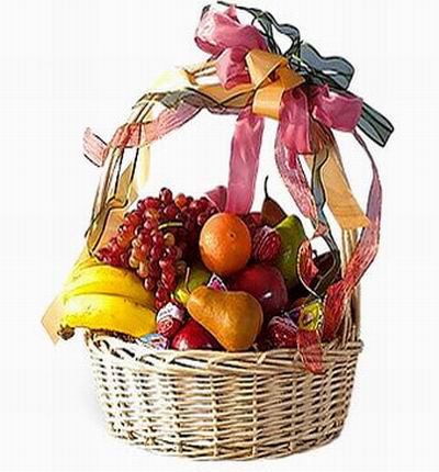 A fruit basket of 3 Bananas, 2 red Apples, 3 Pears, 1 Orange, two bunches of Globe Grapes with a sprinkle of fruit flavored Candies.