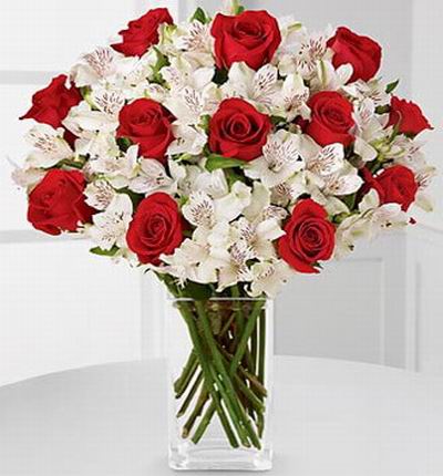 12 red roses, snowy white Peruvian lilies accented with Israeli ruscus greens.