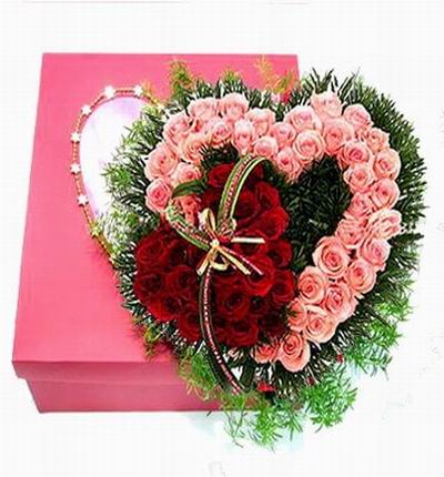 Heart Shaped Design of 25 pink roses and 25 red roses with green fillers in box.