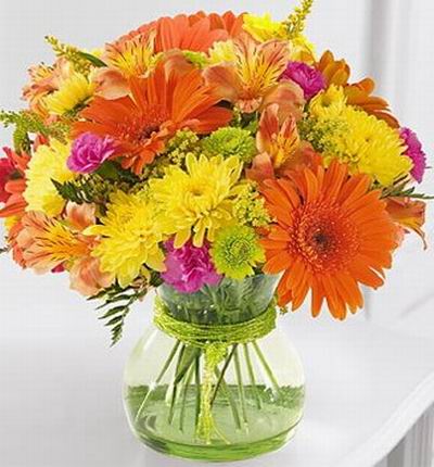 Brightly colored bouquet of orange Gerbera daisies, yellow poms, hot pink mini carnations, and vivid green button poms