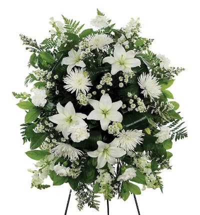 A classic white floral sympathy standing spray, with white carnations, white mums, snapdragons and Monte Casino. Hand arranged by a florist this all white funeral standing spray is a classic gift to send in honor of someone important. Measures 32