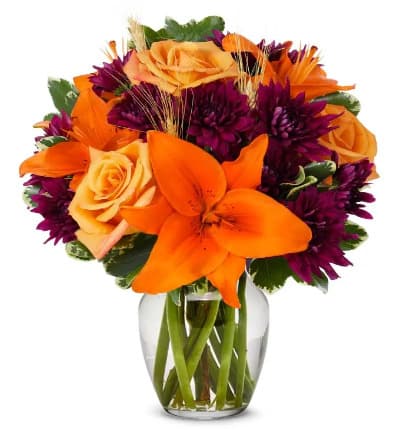 * Orange Roses
* Orange Lilies
* Purple Cushion Poms
* Clear Fluted Vase