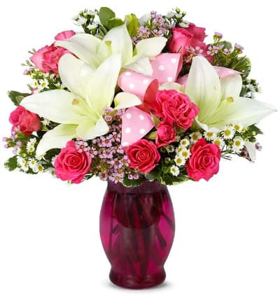 * Pink Spray Roses
* White Lilies
* Pink Waxflower
* White Monte Casino
* Hand Tied Pink Bow
* Keepsake Pink Vase