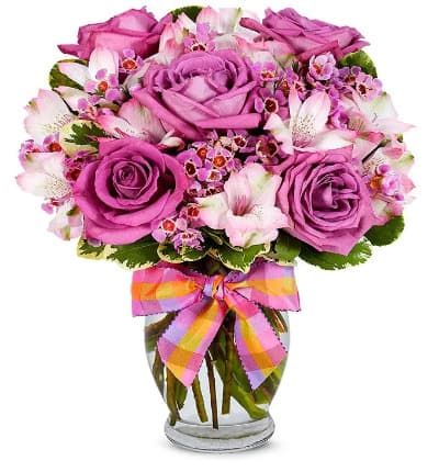 * Purple Roses
* Pink Alstroemeria
* Purple Waxflower
* Clear Fluted Vase
* Decorative Ribbon