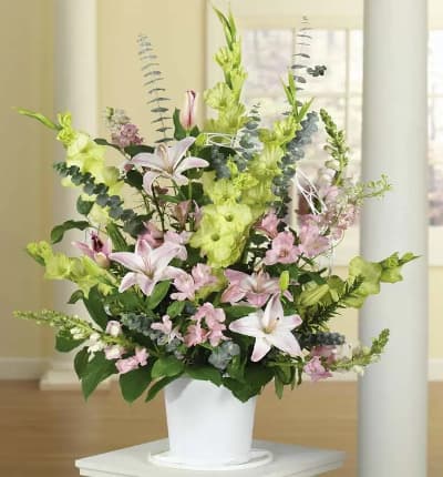 A beautiful sympathy floral arrangement of pink snapdragons, lilies, green gladiolus and alstroemeria. These pastel mixed flowers are a lovely tribute to a life lived to the full.  Arrangement measures approximately 35