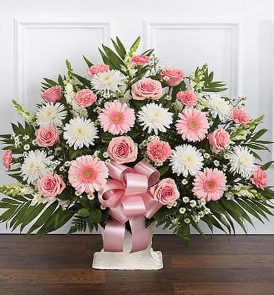 Send a symbol of your love with this Pink and White Flower Funeral Floor Basket with pink roses, white mums, snapdragons and pink carnations. The pink and white floor basket for sympathy is wrapped with a decorative pink ribbon. Medium arrangement measures approximately 32