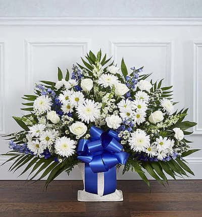 A memorable sympathy floor basket is a wonderful way to send your sympathy. Created with fresh flowers including white roses and snapdragons with blue delphinium. Delivered in a keepsake basket with a decorative ribbon. Available for delivery today, or in a date in the future. Medium arrangement measures approximately 32