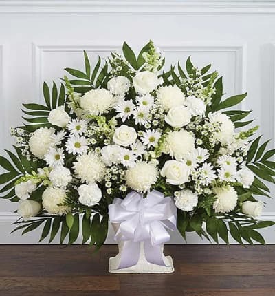 A beautiful sympathy floor basket hand arranged with stunning white flowers. Created with fresh seasonal floral stems, including white roses, spider mums and snapdragons. Hand arranged by a local florist and delivered with care. Medium measures approximately 32