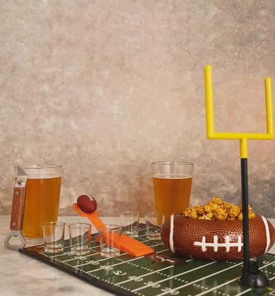 This exciting Tailgate At Home Gift Set includes everything you need to play a table top Football Party game, and then some! We also include a decorative football snack bowl, custom beer glasses and a beer bottle opener. Whether your team wins or loses, you'll still be having a great time! Please note that this gift does not include the beer shown.

Includes:
* Football Shot Game
* Football Bowl Set
* Two Custom Beer Glasses
* Wooden Beer Opener