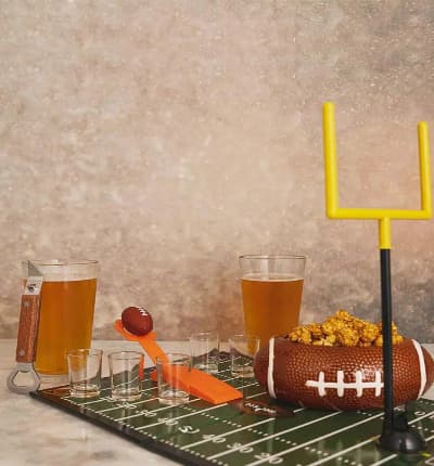 This exciting Tailgate At Home Gift Set includes everything you need to play a table top Football Party game, and then some! We also include a decorative football snack bowl, custom beer glasses and a beer bottle opener. Whether your team wins or loses, you'll still be having a great time! Please note that this gift does not include the beer shown.

Includes:
* Football Shot Game
* Football Bowl Set
* Two Custom Beer Glasses
* Wooden Beer Opener