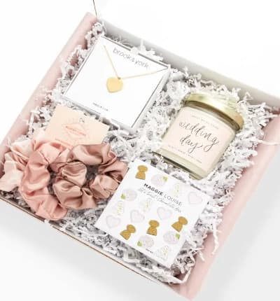 This deluxe gift set is perfect for the lovebirds in your life. Whether she's preparing for her special day, celebrating an anniversary, or simply deserving of some pampering, we've got you covered! These luxury gifts are curated from brands with a shared philosophy and values, coming from America Made or Women Led Businesses.

Includes:
* brook & york - Isabel Heart Pendant
* Sweet Water Decor - Wedding Day Soy Candle
* Mulberry Grand - Blush Satin Scrunchie Set
* Maggie Louise Confections - Let's Toast